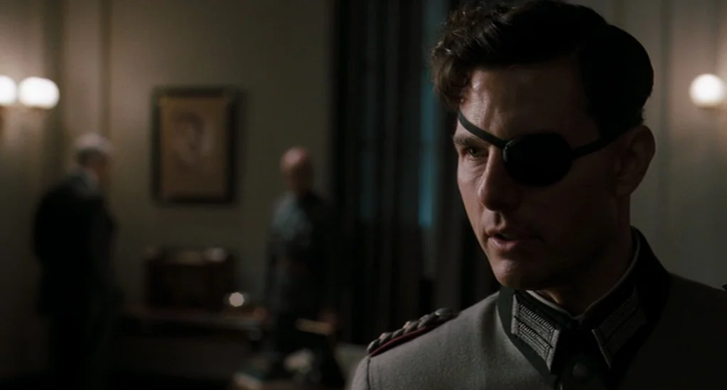 Valkyrie (2008) movie still: medium — A dimly lit room features dark wood furniture and muted wall coloring. A military officer in a grey uniform…
