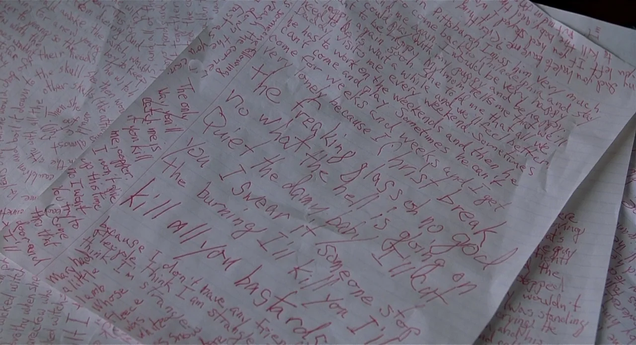 The Sixth Sense (1999) movie still: closeup — Several sheets of white notebook paper are spread across a surface. Each page is completely filled…