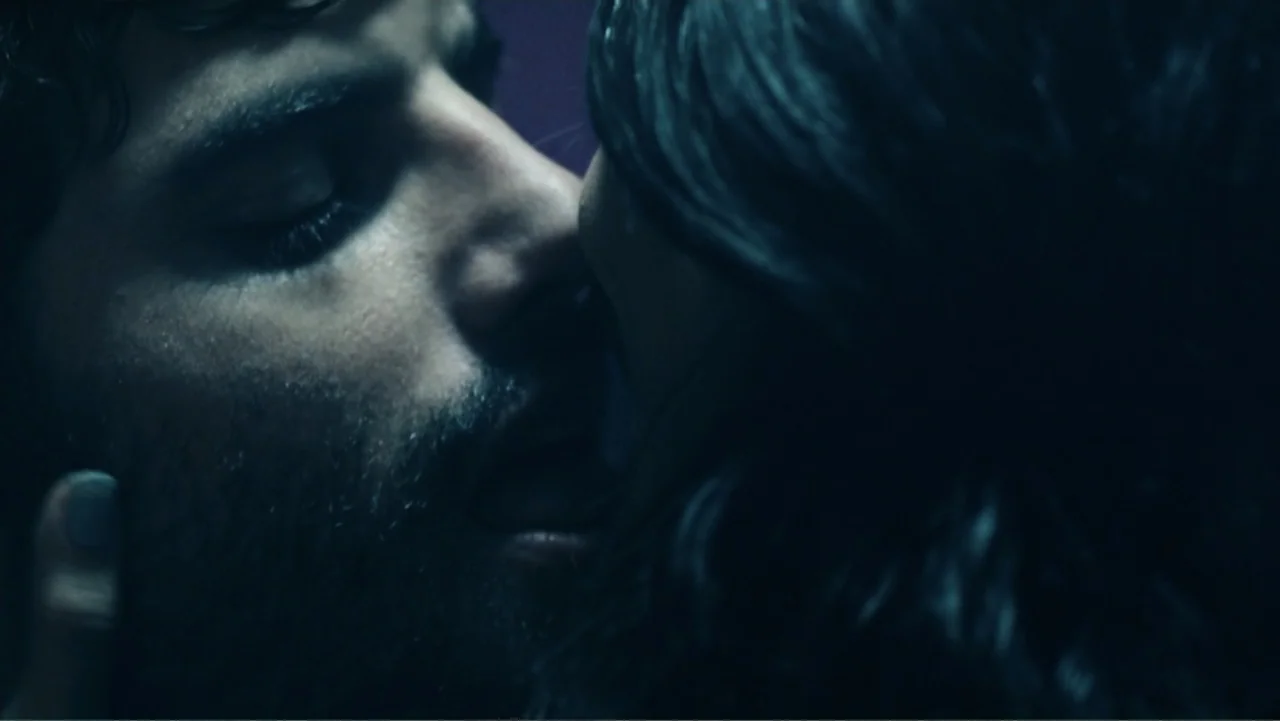 Alice in Marialand (2014) movie still: closeup — An interior space is dimly lit by cool-toned light sources. A man and a woman are shown in a…