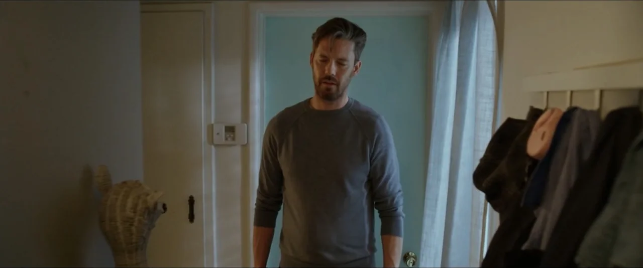 Gatlopp: Hell of a Game (2022) movie still: medium — A residential entryway features a light blue door and wall-mounted coat hooks. A man in a grey…
