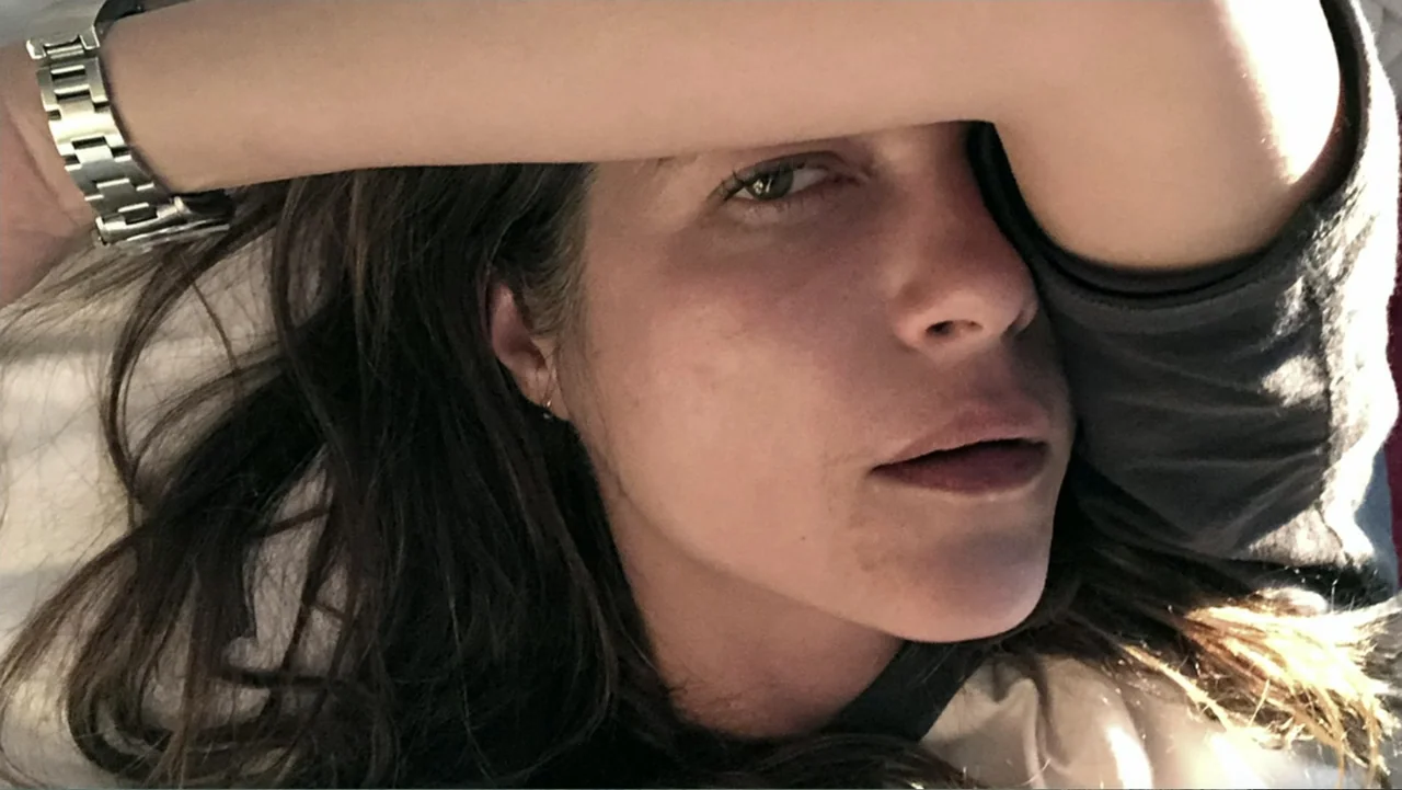Introducing, Selma Blair (2021) movie still: closeup — A bright domestic interior with a white surface visible beneath the subject. A woman lies on…