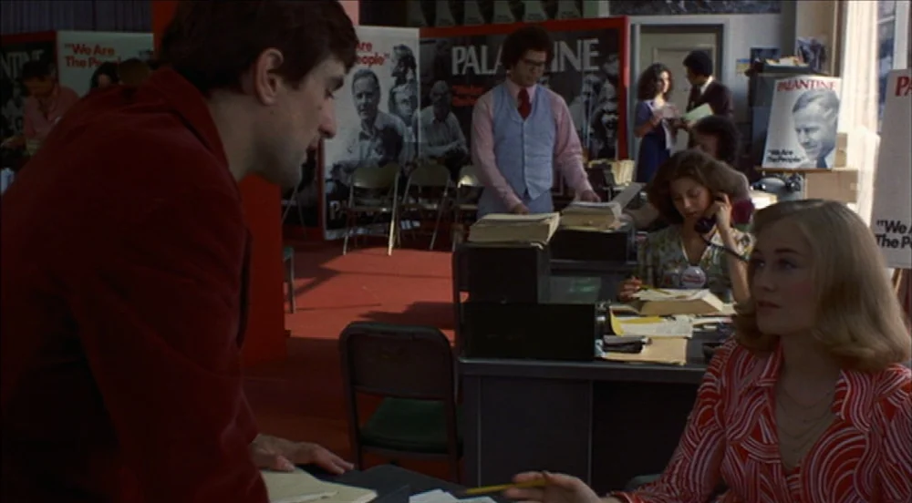 Taxi Driver (1976) movie still: medium — A campaign office interior filled with political posters and desks for campaign workers. A man in a red…