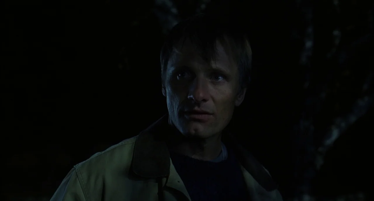 A History of Violence (2005) movie still: closeup — A dark outdoor environment at night with blurred shapes visible in the background. A man looks…