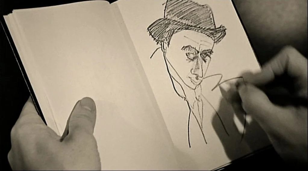 Wings Of Desire (1987) movie still: closeup — A pair of hands holds an open notebook with a sketch on the right page. The sketch depicts a man…