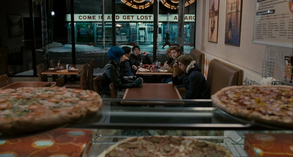 Scott Pilgrim Vs The World (2010) movie still: wide — A quiet fast-casual pizza place with large glass windows overlooking a dark street. Several…