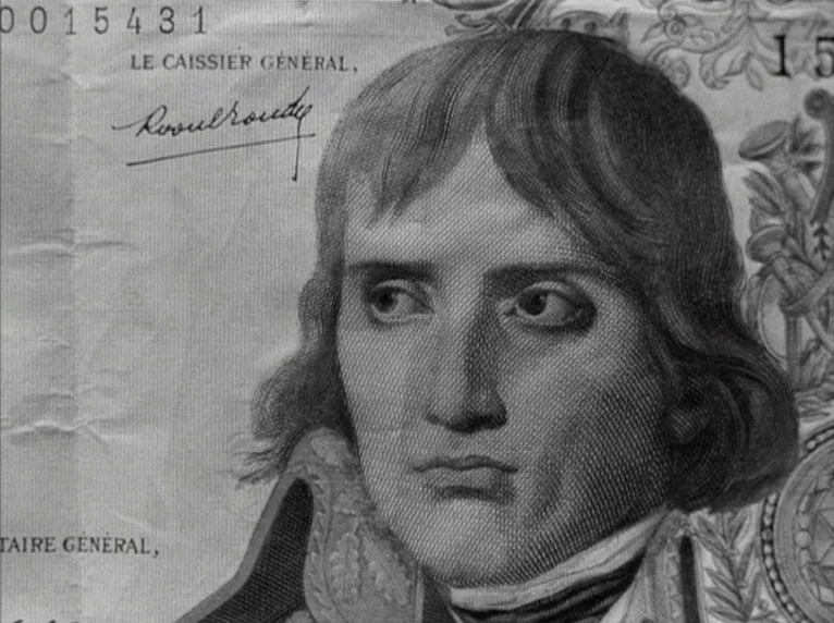 Band of Outsiders (Bande à part) (1964) movie still: closeup — A close-up view of a printed banknote featuring an engraving of a man. The paper…