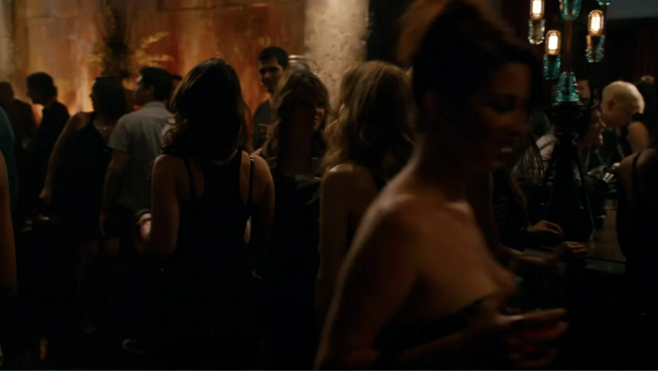 This Is 40 (2012) movie still: medium — A crowded, dimly lit nightclub interior has textured warm-toned walls and an ornate glass lamp. Multiple…