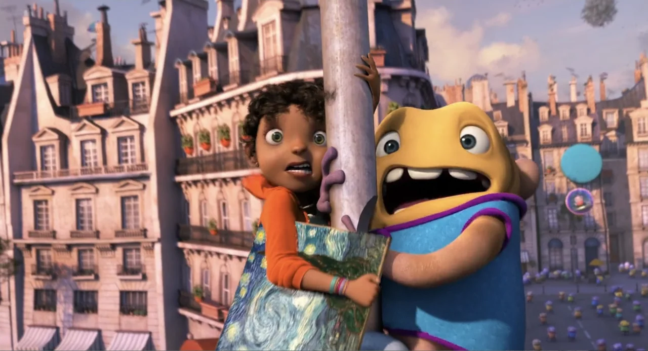Home (2015) movie still: medium — A Parisian-style residential street features tall stone buildings with balconies and shutters. A human girl and a…