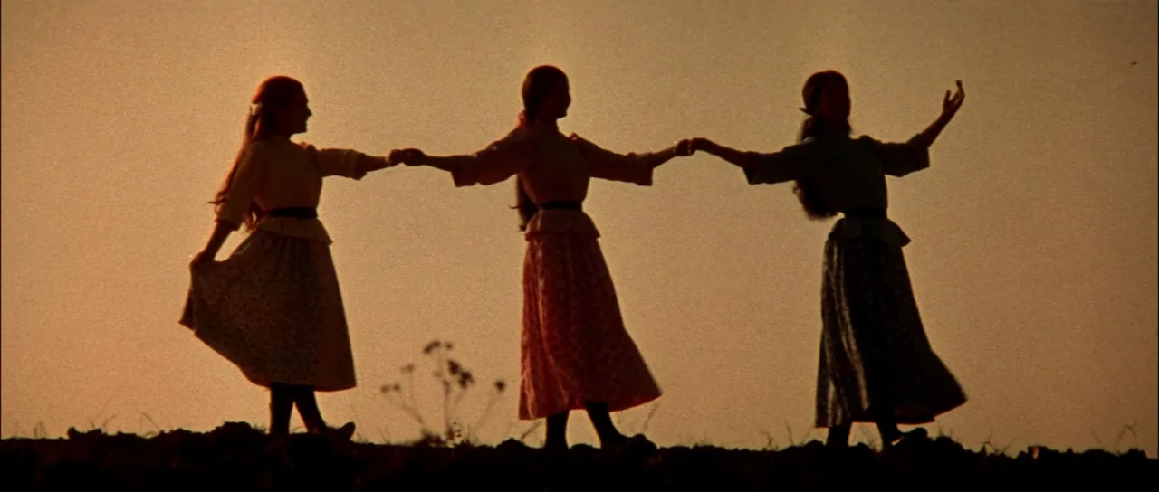 Fiddler On The Roof (1971) movie still: fullbody — Three young women in long skirts hold hands in an open field at sunset. They are captured in…