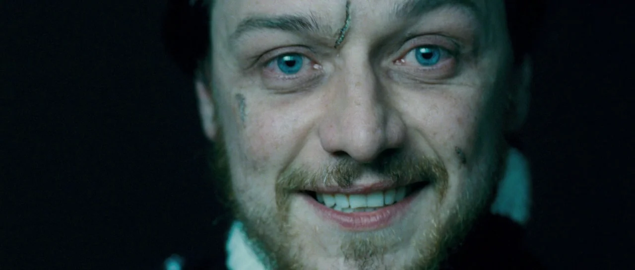 Filth (2013) movie still: closeup — A man's face is centrally framed against a completely dark background. He smiles broadly at the viewer while…