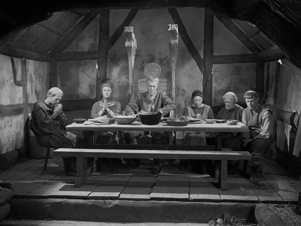 The Virgin Spring (1960) movie still: fullbody — A rustic medieval cottage interior features heavy timber framing and uneven plank flooring. Six…