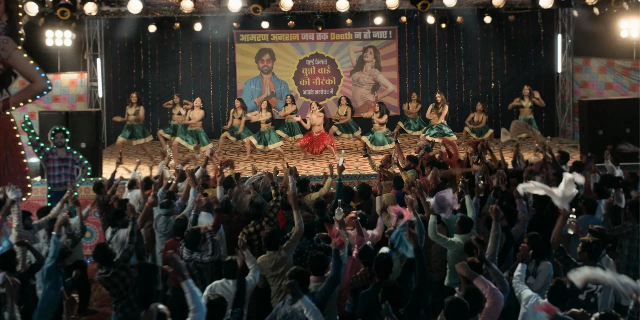 Dry Day (2023) movie still: wide — A crowded performance hall contains a central stage where dancers perform before an audience. Large promotional…