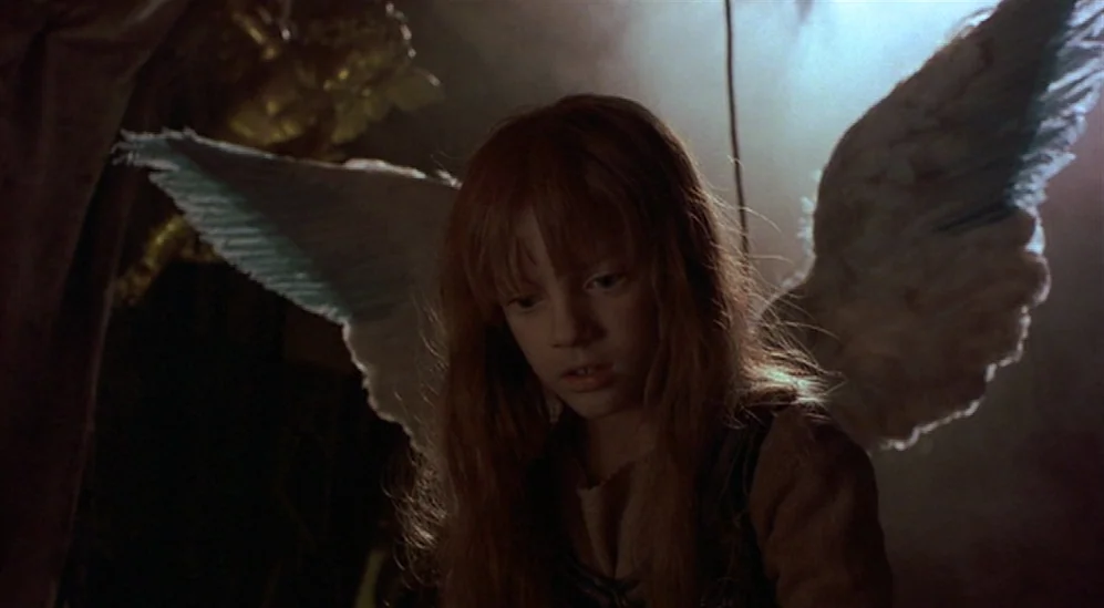 The Adventures Of Baron Munchausen (1988) movie still: medium — A dimly lit, indistinct setting provides a dark backdrop for a small girl. She wears…