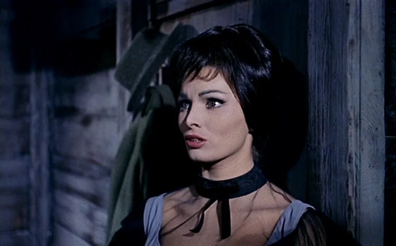 Mill of the Stone Women (1960) movie still: closeup — The interior of a rustic wooden shack has a felt hat hanging on a wall. A young woman with…