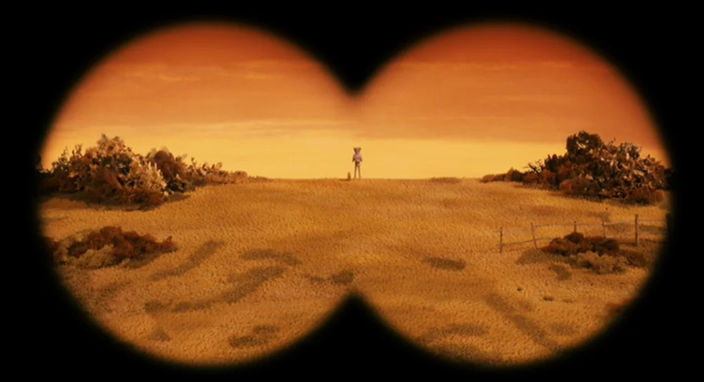 Fantastic Mr. Fox (2009) movie still: wide — A dry, textured field stretches toward a distant, cloudless sunset horizon. A small figure stands in…