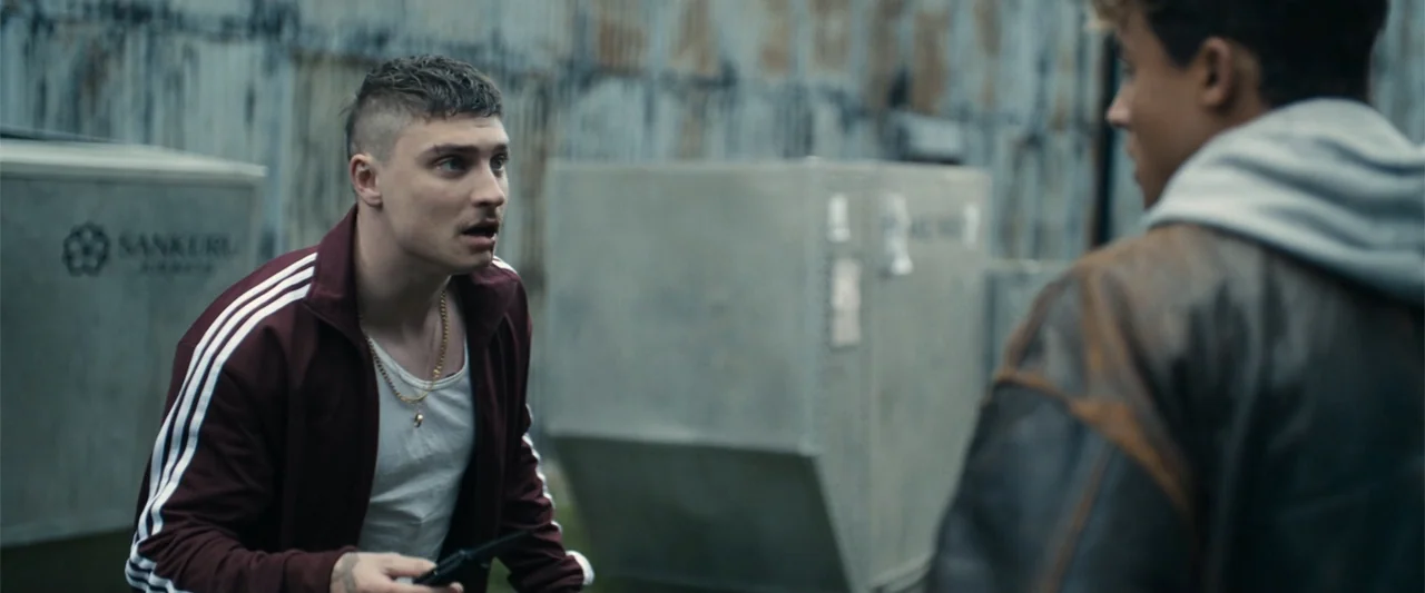 My Fault: London (2025) movie still: medium — An outdoor industrial loading area features metallic panels and large storage containers in…