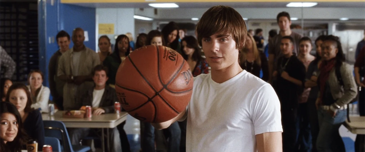 17 Again (2009) movie still: medium — A bustling school cafeteria features blue walls, metal tables, and many teenage students. A young man in a…