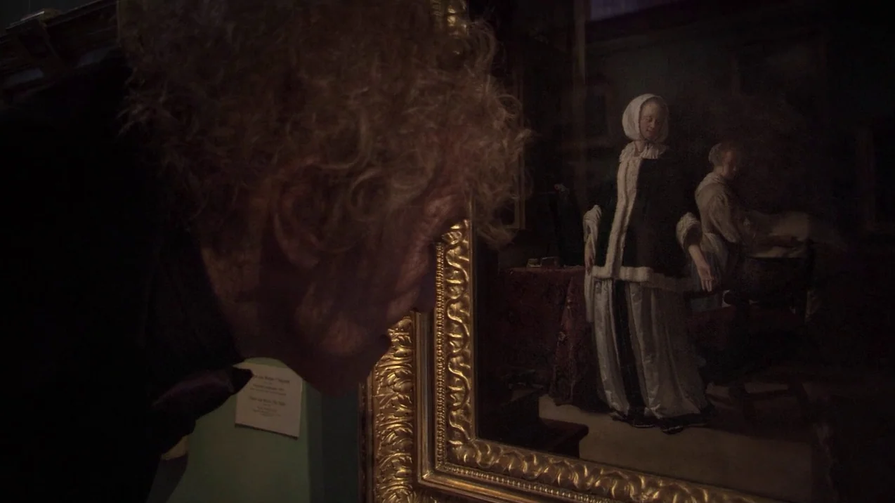 Russian Ark (2002) movie still: medium — An elderly man in a dark jacket examines a painting in a gallery. The ornate gold frame houses a…