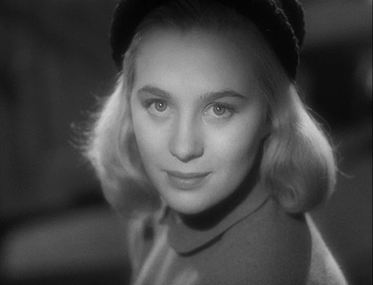 Music in Darkness (1948) movie still: closeup — A close-up studio portrait of a woman wearing a dark cap. The subject stares directly forward with a…