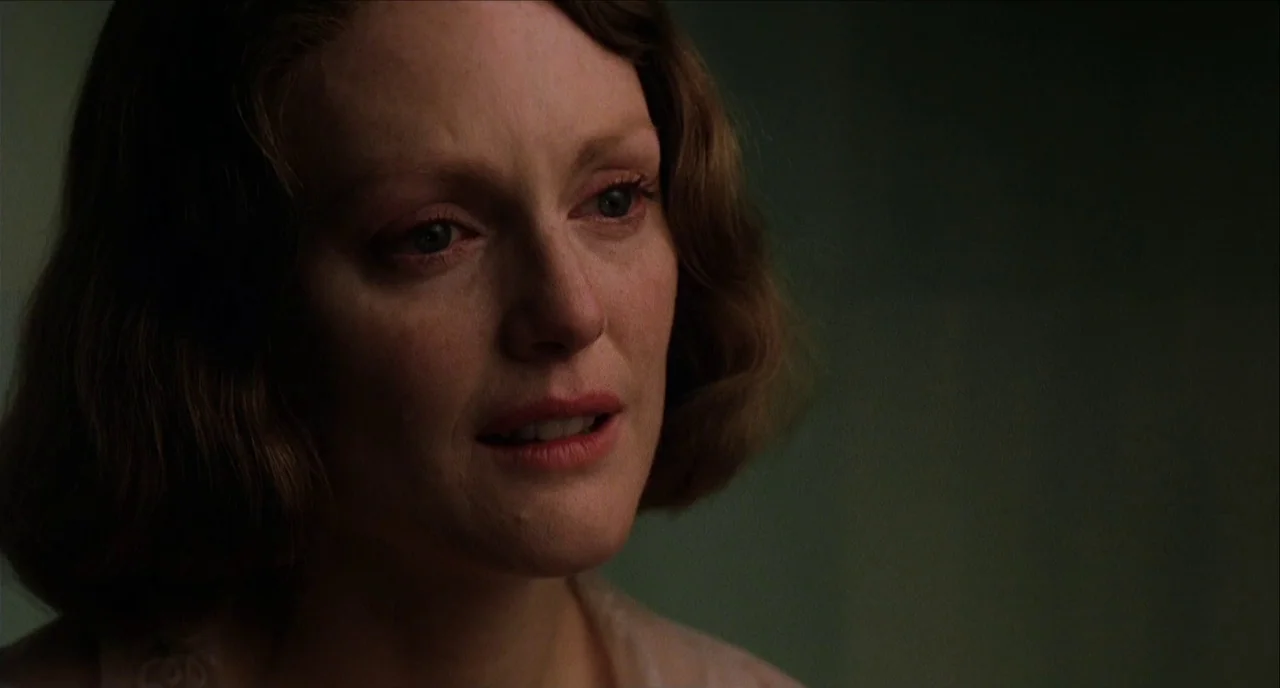 The Hours (2002) movie still: closeup — The interior setting is dimly lit with a muted, monochromatic green-toned background. A woman in her forties…