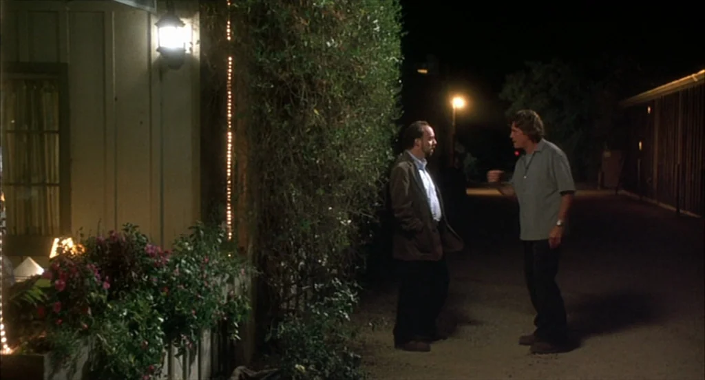 Sideways (2004) movie still: fullbody — A nighttime scene outside a wood-sided building with potted plants and decorative string lights. Two men…