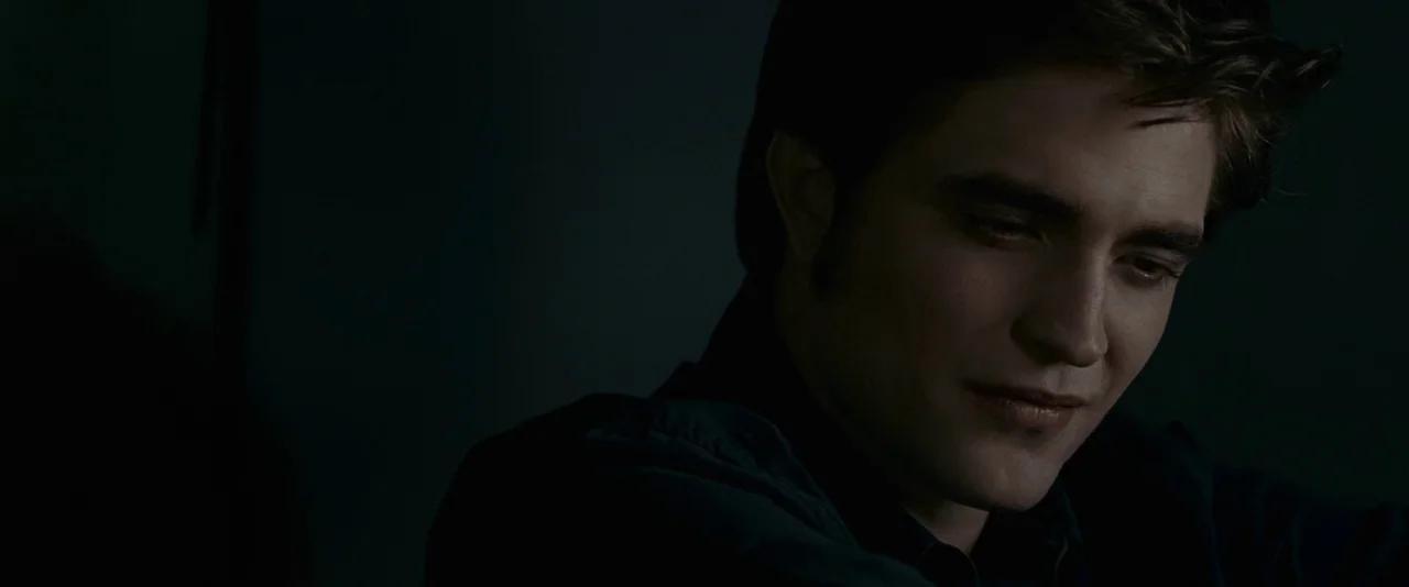 The Twilight Saga: Eclipse (2010) movie still: closeup — A dark room is illuminated by faint light focused on the subject's face. The subject looks…