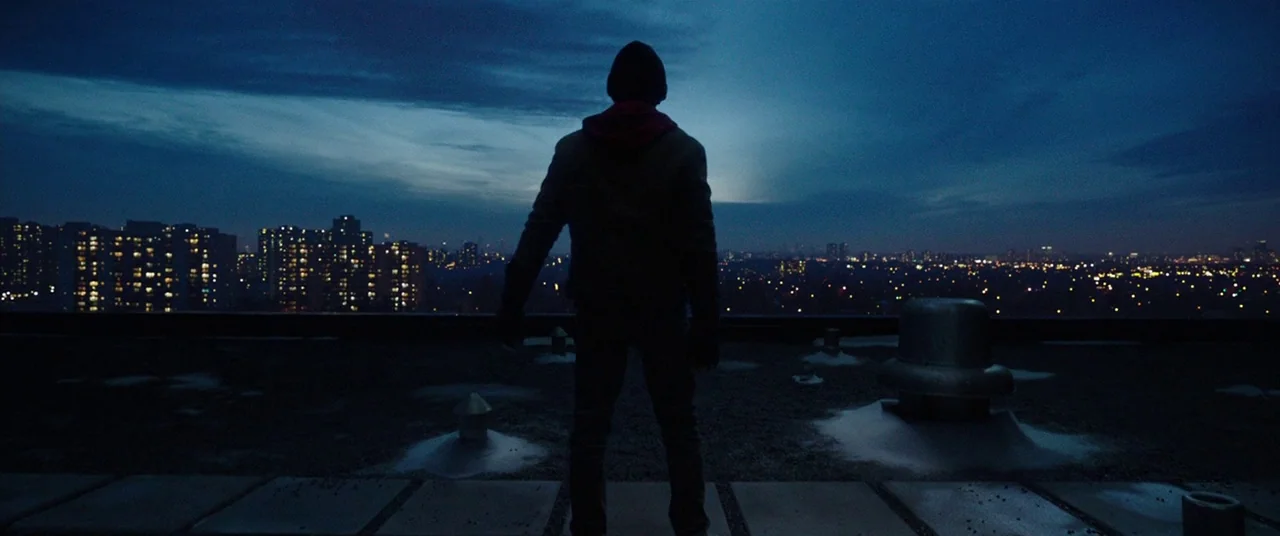 Shazam! (2019) movie still: fullbody — A flat rooftop covered in ventilation equipment overlooks a sprawl of urban apartment buildings. A person…