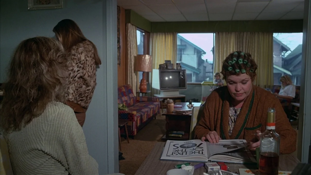Ladies and Gentlemen, the Fabulous Stains (1985) movie still: medium — A 1970s living room features a plaid sofa, a vintage television set, and…