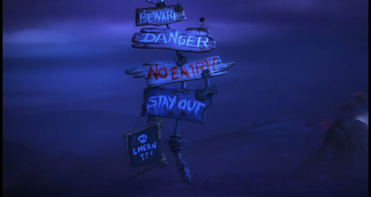 The Lorax (2012) movie still: fullbody — A wooden signpost covered with painted warnings sits in a desolate landscape. Multiple planks with text and…