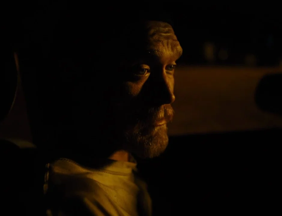 American Honey (2016) movie still: closeup — The interior of a dark car at night with a single light source. A man is sitting in the driver's seat…