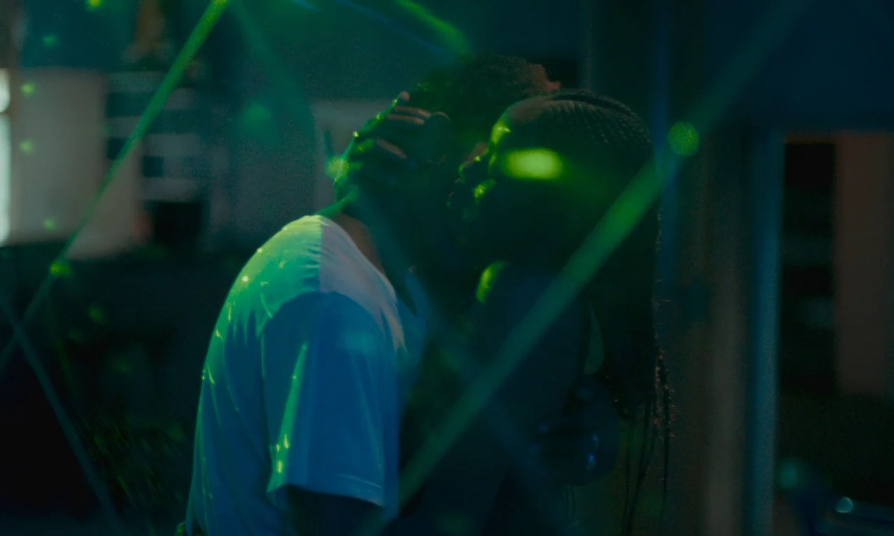 Atlantics (2019) movie still: medium — A dimly lit room is filled with shifting green laser beams and geometric patterns. A man in a white t-shirt…