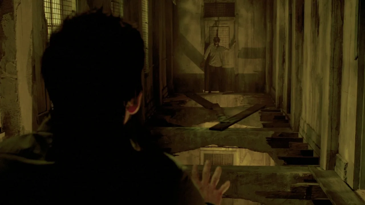 Saw VII: The Final Chapter (2010) movie still: medium — A dilapidated, crumbling hallway features structural gaps in the floor between two figures.…