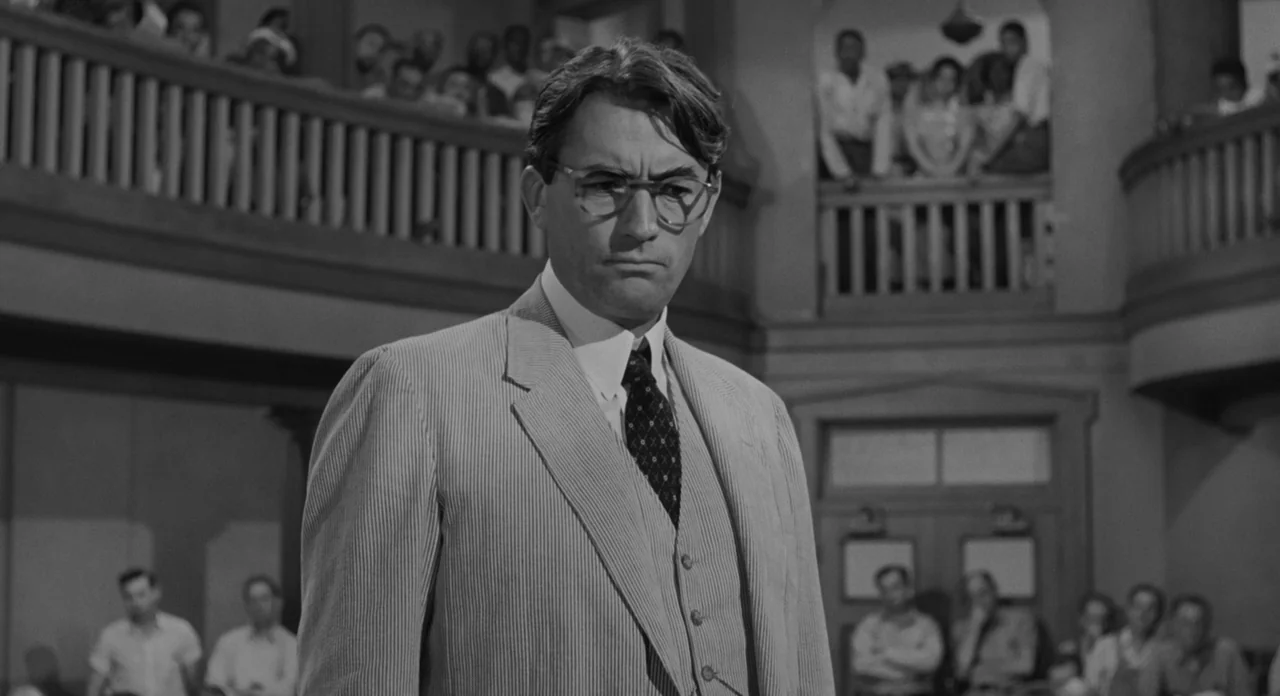 To Kill A Mockingbird (1962) movie still: medium — A wood-paneled courtroom interior features a raised balcony packed with observers looking down. A…