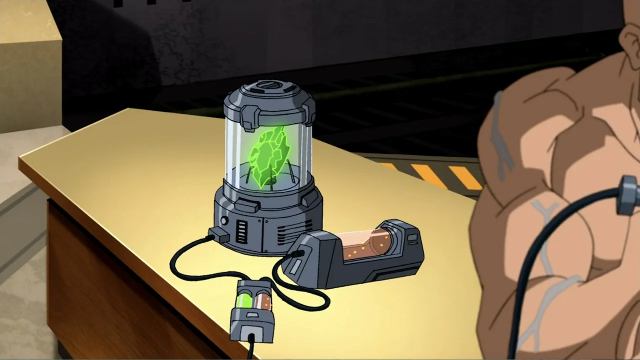 Superman/Batman: Public Enemies (2009) movie still: medium — A metallic table holds a glowing green crystal in a cylindrical glass containment unit.…
