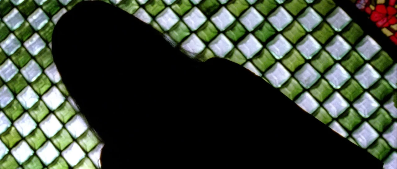 The Strange Colour of Your Body’s Tears (2013) movie still: closeup — A dark, unrecognizable figure is positioned before a grid of square,…