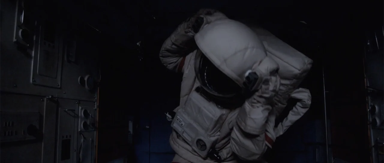 Astronaut: The Last Push (2012) movie still: medium — An interior space module features dark metal walls with recessed control panels and wiring. An…