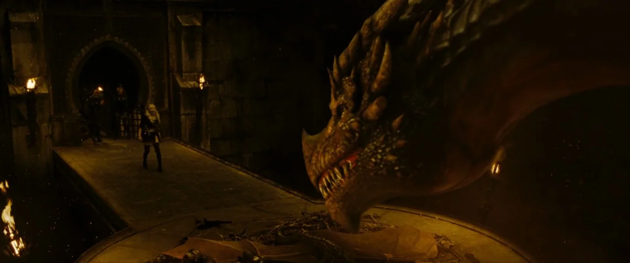 Sucker Punch (2011) movie still: wide — A dark stone bridge connects to a vaulted gateway at night with firelit illumination. A woman approaches a…