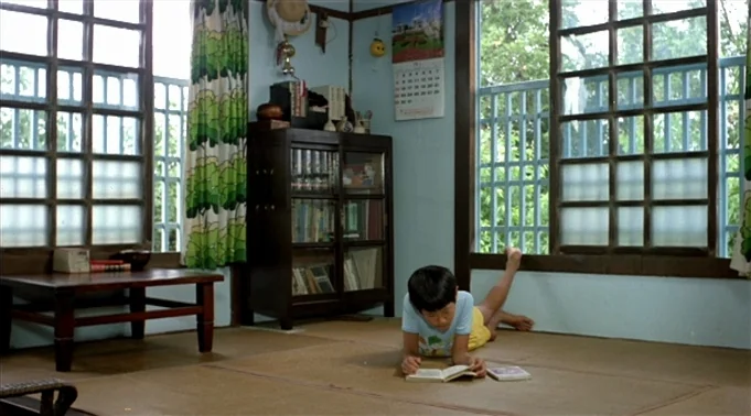 A Summer at Grandpa’s (1984) movie still: wide — A Japanese-style interior features straw tatami mats and large windows with grid panels. A young…