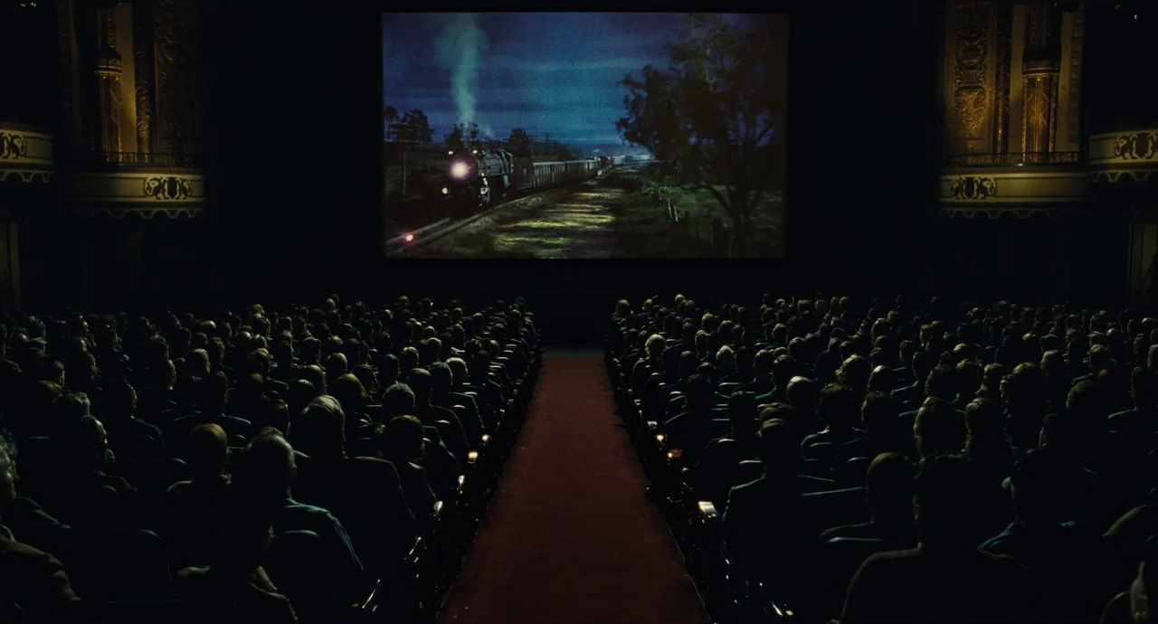 The Fabelmans (2022) movie still: wide — An ornate, classic-style movie palace is filled with a seated audience in darkness. The bright projection…