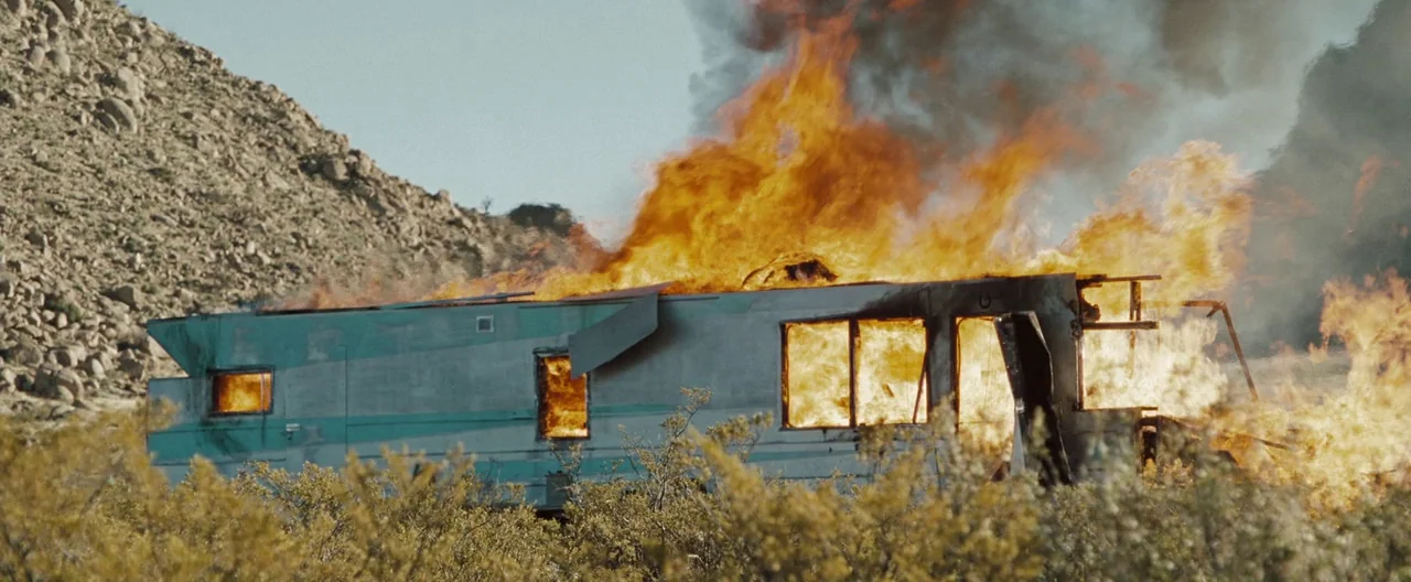The Burning Plain (2008) movie still: wide — An abandoned mobile home sits in a sparse desert landscape beneath a rugged hill. The structure is…