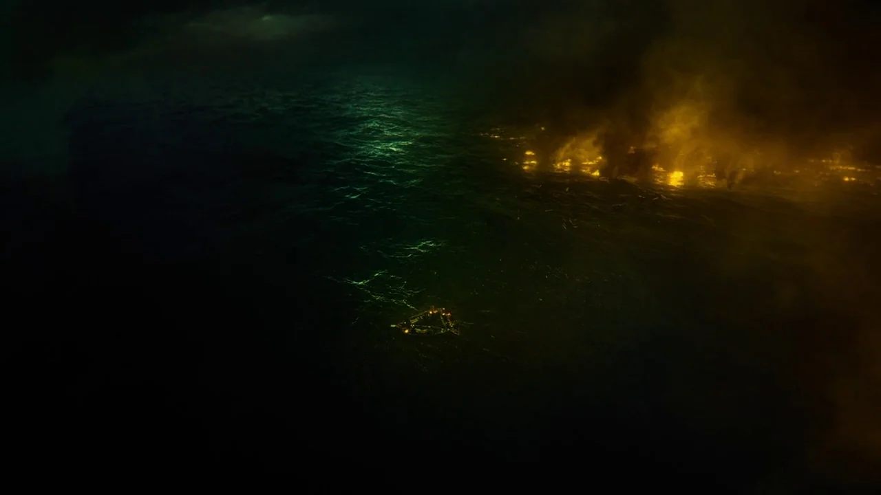 In The Heart of the Sea (2014) movie still: establishing — A vast, dark expanse of ocean is lit by a large, burning debris field. Small scraps of…