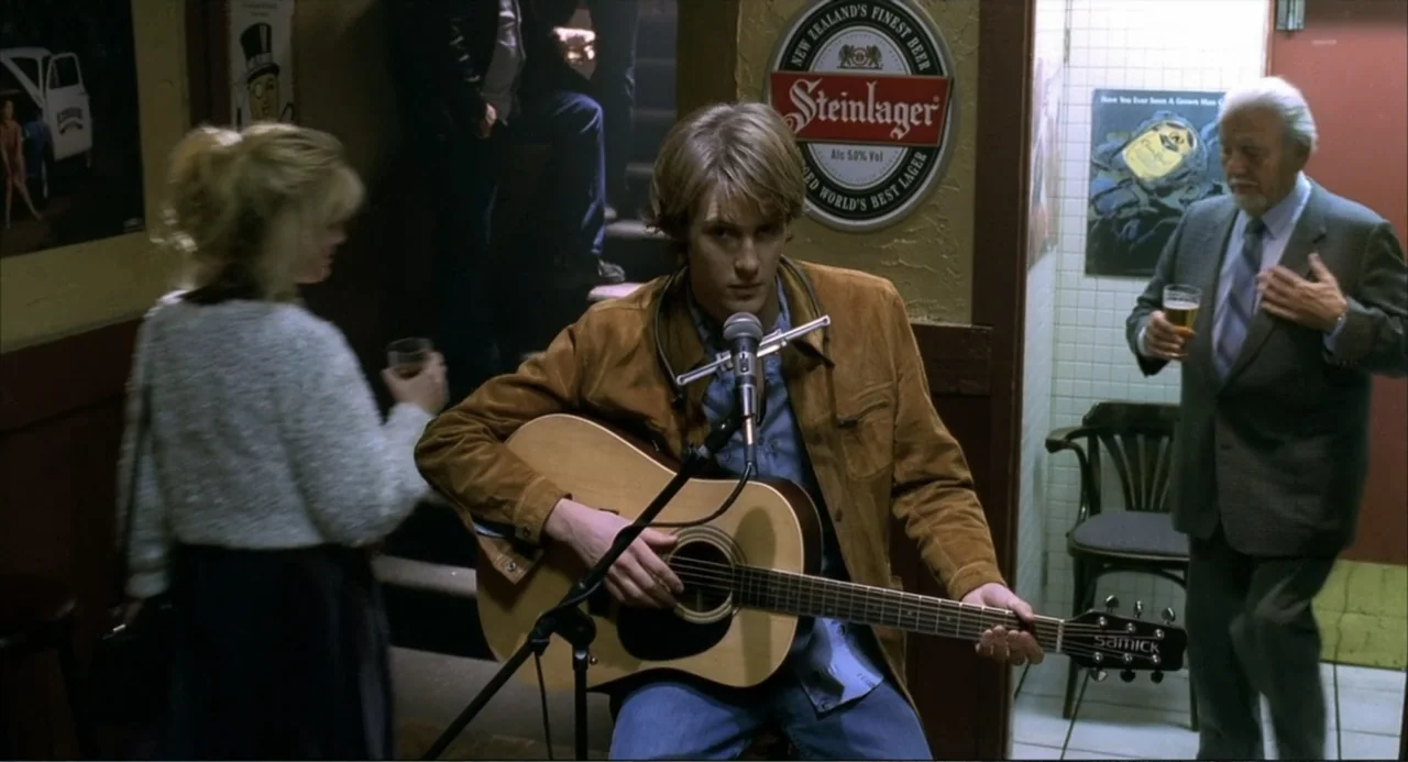 Josie and the Pussycats (2001) movie still: medium — A pub interior features brown wood paneled walls with circular beer advertisements hung…