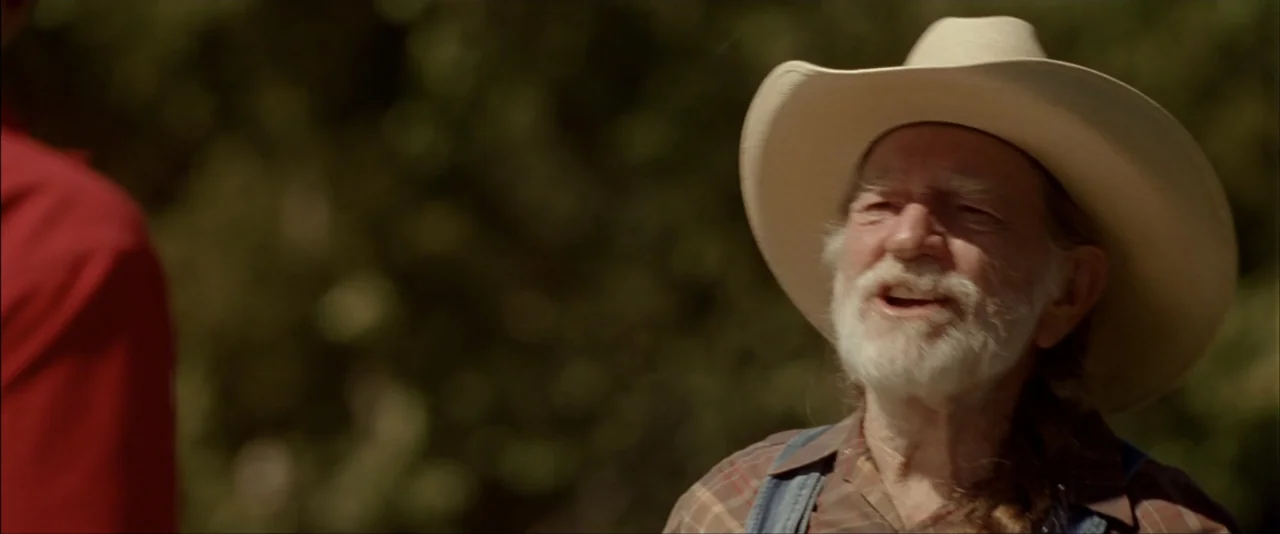 The Dukes of Hazzard (2005) movie still: medium — An outdoor area with blurred green foliage in the background under natural sunlight. An elderly…