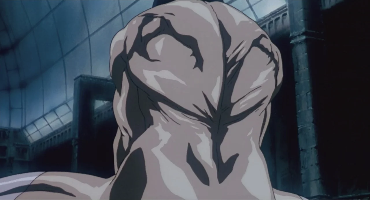Ghost in the Shell (1995) movie still: closeup — A dark industrial hall with arched metal ceilings and deep shadows. A muscular figure stands facing…