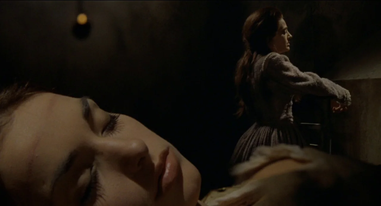 Beatrice Cenci (1969) movie still: medium — A dark stone interior features a woman resting in the foreground. Another woman stands near a ledge in…