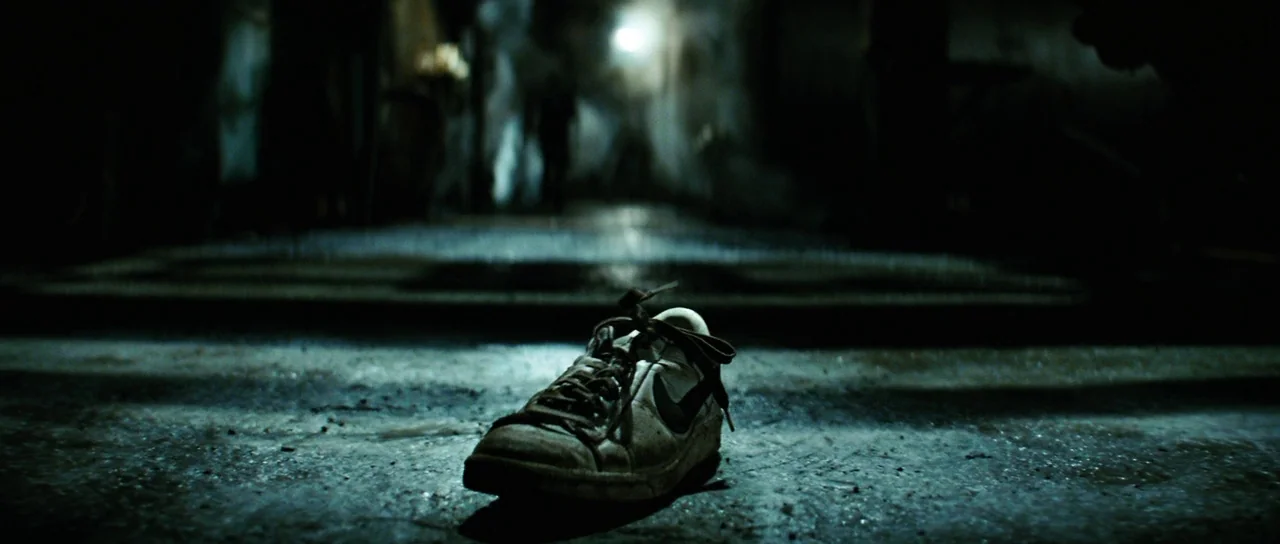 The Incredible Hulk (2008) movie still: closeup — A single dirty sneaker sits alone on wet, dark pavement at night. Rain falls in the background…
