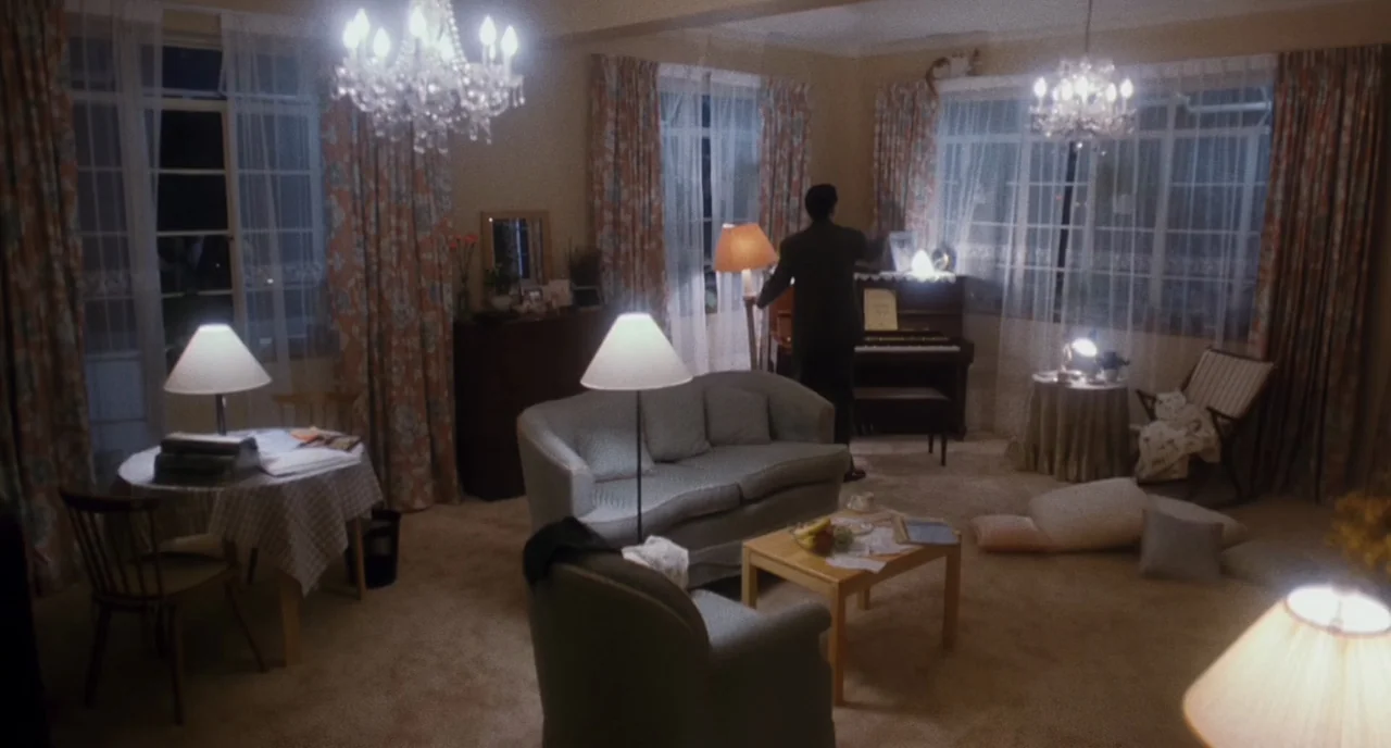 The Killer (1989) movie still: wide — A spacious 1980s-style room features floral curtains, two crystal chandeliers, and wall-to-wall carpeting. A…