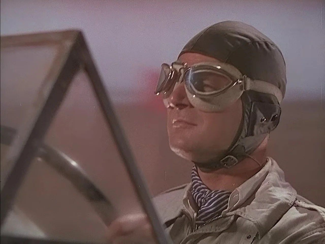 Pandora and the Flying Dutchman (1951) movie still: closeup — A close view inside the cockpit of a vintage propeller aircraft. A pilot wearing a…