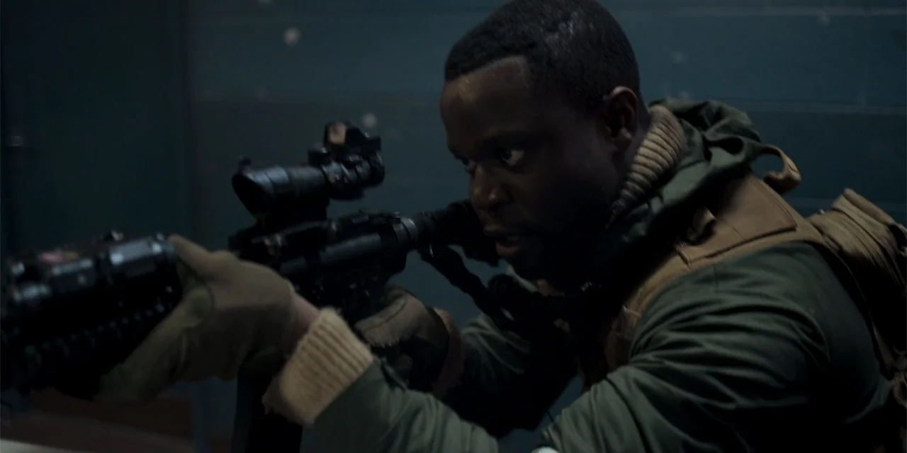 Mi última bala (1998) movie still: medium — A dimly lit interior corridor features dark walls and shadows. A man in tactical gear holds a rifle and…