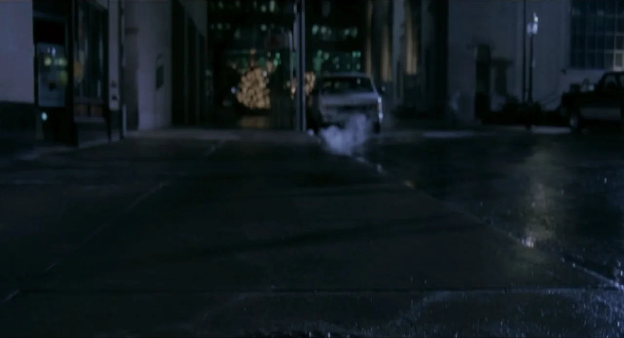 Foolproof (2003) movie still: establishing — A dark urban street at night features wet asphalt and low-hanging steam.